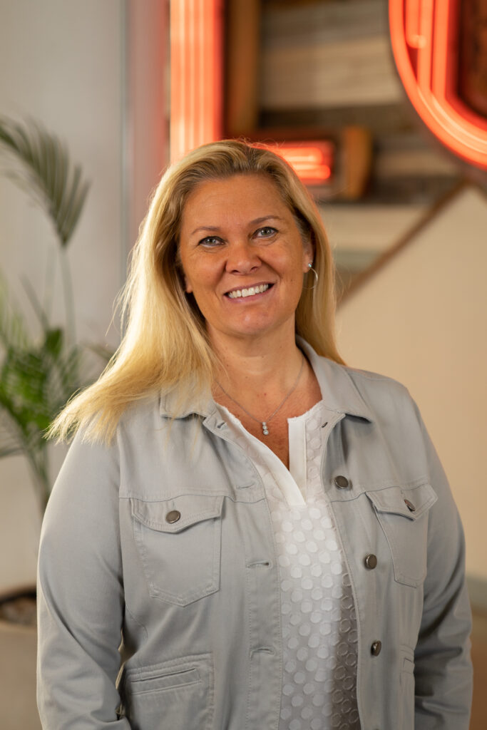 Headshot for Ann Schreiber - Blonde female in grey jacket and white shirt