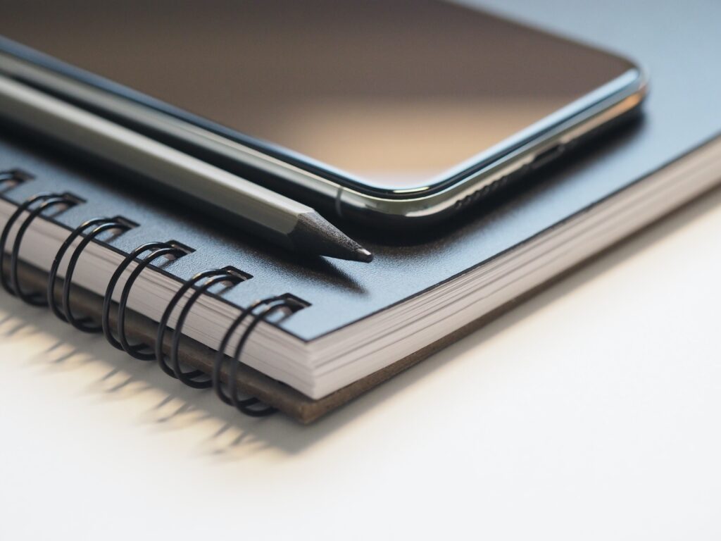 Closeup photo of black notebook and mobile device. Blogging for beginners.