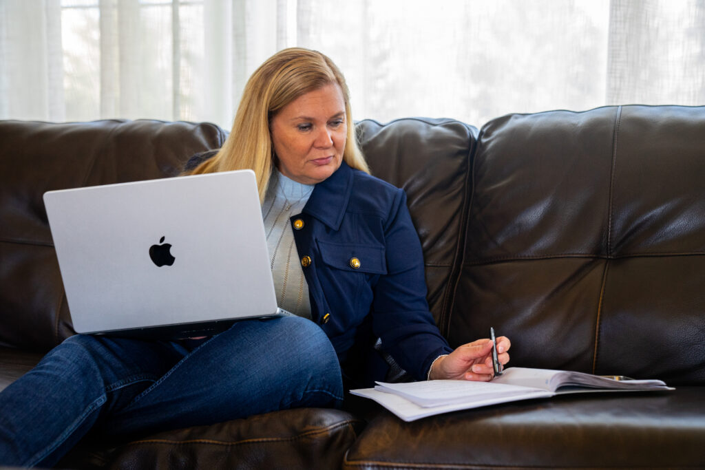 Copywriter sitting on couch with laptop on lap - working on lead generation.